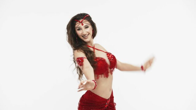 A professional dancer dances oriental belly dance. Sexy woman in red lingerie dances a seductive dance in a white studio. Professional dance trainer. Costume for oriental dances.