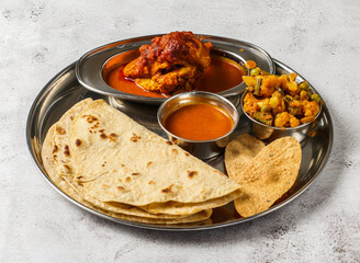 chicken thali set with chicken korma, mixed vegetable of aloo gobi matar, shorba and chapati served in dish isolated on background top view of indian spicy food