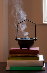 Natural incense smoke coming out from a cast iron incense burner in front of a window standing on...