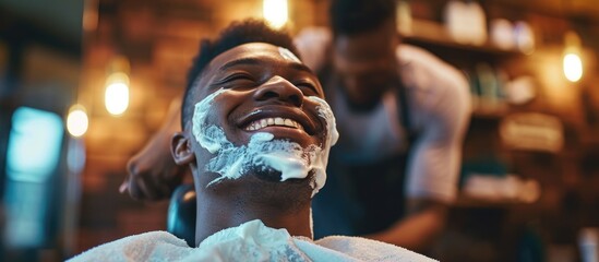 Pictures of a happy young black man getting a professional shave at the barber shop.