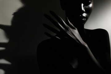 The silhouette of a black woman in the dark with her hands raised in front of her face. - obrazy, fototapety, plakaty