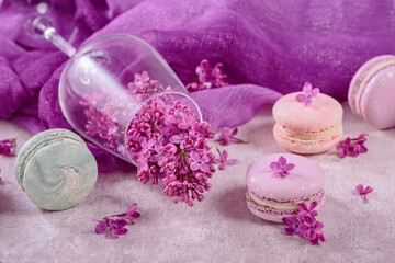 Obraz na płótnie Canvas Sweet pastel french macaroons and lilac flowers on light gray background. Beautiful composition for bakery and pastry shop