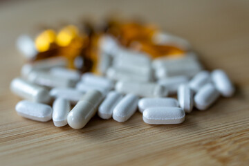 Fototapeta na wymiar closeup of white, yellow medicine capsules on a wooden table.