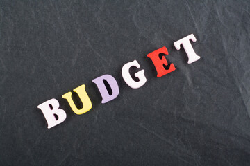 BUDGET word on black board background composed from colorful abc alphabet block wooden letters, copy space for ad text. Learning english concept.