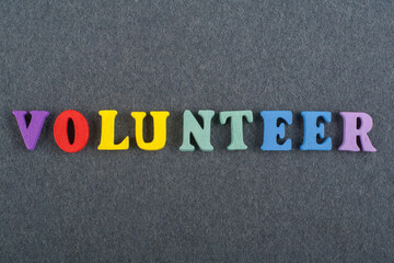 VOLUNTEER word on black board background composed from colorful abc alphabet block wooden letters,...