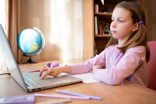 Online education of children. Girl schoolgirl teaches a lesson online using a laptop video chat call conference with a teacher at home.studying, participating in online conference, sitting at desk