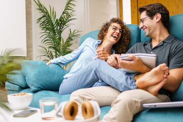 Cheerful couple with pages in living room