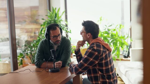 Male friends doing video podcast, talking about difficult topics, sharing sad, hurtful stories. Influencers making live video for social media, creating online content.
