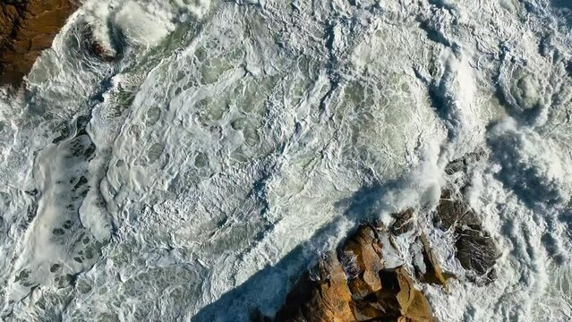 Slow motion drone fotage over bubbling Blue Ocean Water with White Foam Surfaces on a sunny day