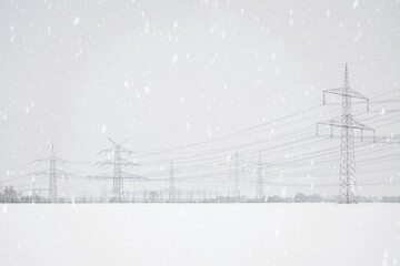 A lot of high-voltage power line in winter, electrical energy transmission tower overhead line masts, high voltage pylons as power pylons on the fields in winter with lots of snow on the fields - obrazy, fototapety, plakaty