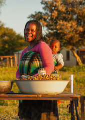 village street vendor, african woman with baby carry in the back , selling peanuts