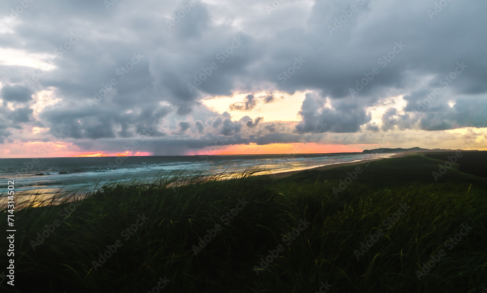 Wall mural the sun sets behind rain clouds along the coast of the pacific ocean in oregon casting light on the 