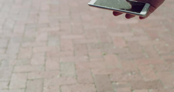 Screen, crack and phone of person in accident, break or drop on pavement floor. Man, click and hand press on broken smartphone from drop on ground with unresponsive technology from mistake or fail