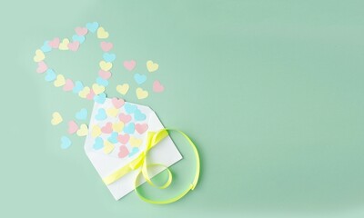 Paper craft for Valentine's Day.  On a green background there is an applique of colored paper hearts in the shape of a heart flying out of an envelope.  Handmade concept, Valentine's Day holiday.