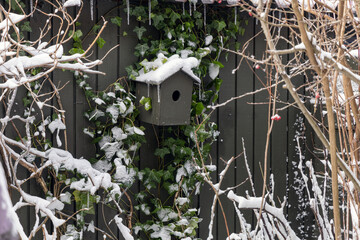 Birdhouse covered with snow in the garden in winter.