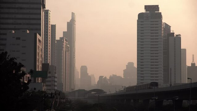The cityscape of Bangkok is obscured by a thick blanket of dust and pollution . The heavy air pollution, filled with fine particulate matter (PM2.5), creates a hazy and oppressive atmosphere. 