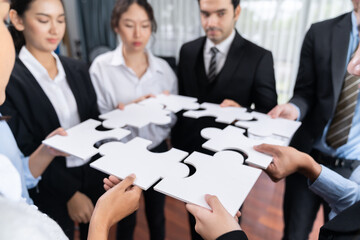 Multiethnic business people holding jigsaw pieces and merge them together as effective solution...