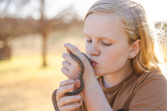 Pre-teen adolescent boy kissing pet children's python snake