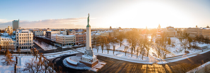 Beautiful sunrise panorama  over Riga by the statue of liberty - Milda in Latvia. The monument of freedom. - obrazy, fototapety, plakaty