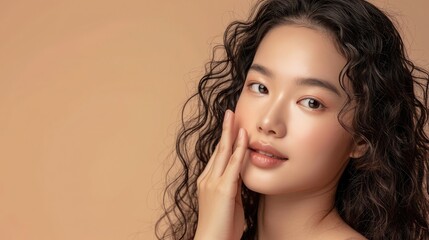 Young Asian beauty woman curly long hair with korean makeup style touch her face and perfect skin on isolated beige background. Facial treatment, Cosmetology, plastic surgery.