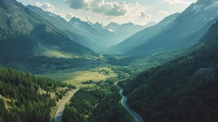  an aerial view of a mountain valley with a winding road in the foreground and a valley in the middle with trees on both sides and mountains in the background. - obrazy, fototapety, plakaty