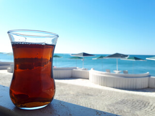 A glass of black tea in front, the beach in the back.