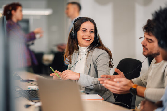 A telemarketer is sitting at call center and having a phone call.