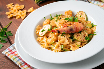 Piatto di deliziosa pasta condita con zucchine e gamberi, cibo italiano 