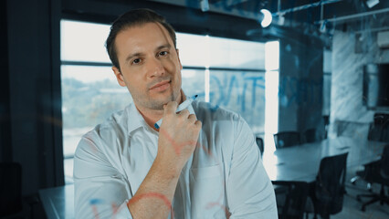 Smart businessman thinking about start up project in front of glass board. Smiling male project...