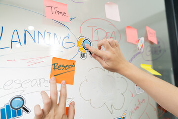 Closeup of professional businesswoman hand put and stick the colorful sticky notes on whiteboard...