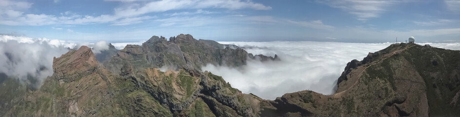 Aerial panoramic view at the Pico do Areeiro mountains and Pico Ruivo, Madeira Island highest points, low clouds and cinematic effect, Madeira Island, Portugal