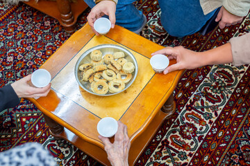 hands holding eid sweets and coffee cups, multigenerational family