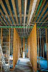 Under-construction home interior with wooden framing, electrical wiring, and ladder on site
