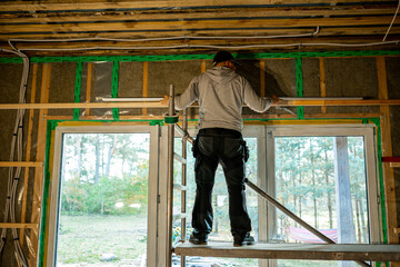 Skilled worker installing windows in a new construction with exposed insulation and framing