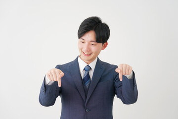 下を指差す若いビジネスマン　白背景
