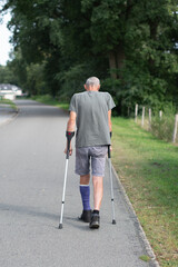 A man with a broken leg is walking down the street, on his left leg he has a special boot for walking