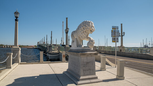 Marble lion statue guarding the entrance to Lions Bridge in St. Augustine with clear blue skies.