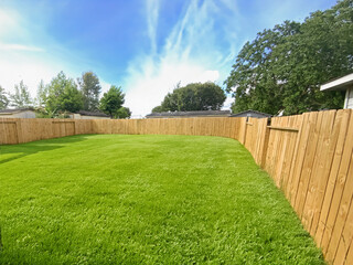 Brand new wood fence around a home backyard.