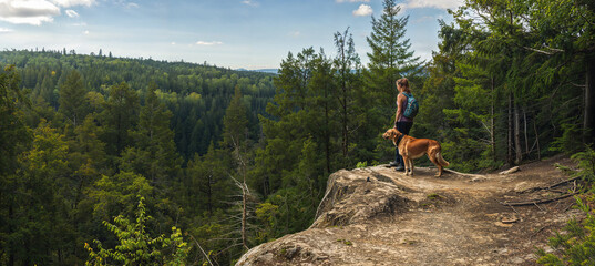 Woman and dog hiking on a trail in the forest