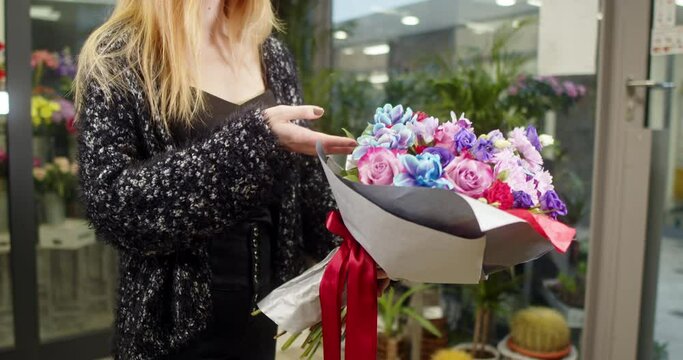 Girl shows a bouquet of blue rose, Alstromerie, Eustoma, Fresie, Chrysanthemy in a flower store