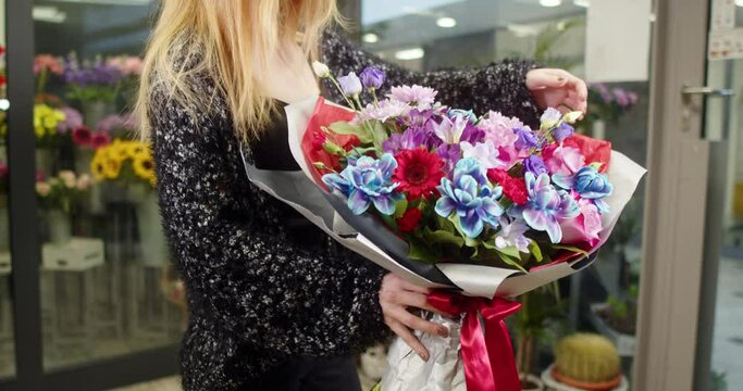Girl shows a bouquet of blue rose, Alstromerie, Eustoma, Fresie, Chrysanthemy in a flower store