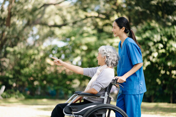 Obraz premium Asian young caregiver nurse support senior older female walking outdoors. Specialis doctor help and take care of elderly mature.
