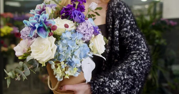 the girl shows a box of flowers with blue tulips, matiolas, white roses, chrysanthemum santini
