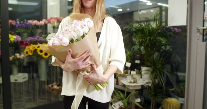 the florist shows a bouquet of white and purple tulips wrapped in kraft paper.