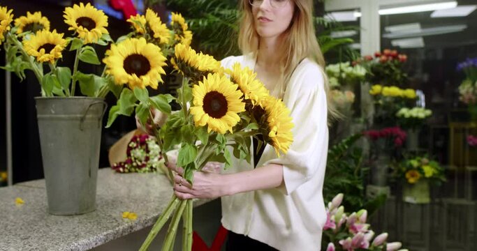 A florist at a flower store assembles a bouquet of sunflowers