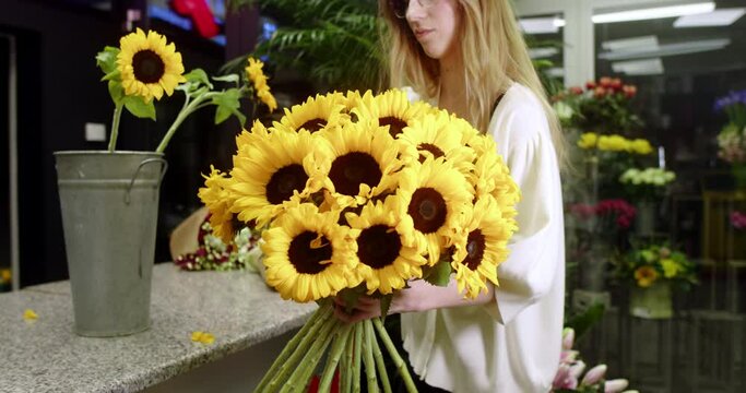 A florist at a flower store assembles a bouquet of sunflowers