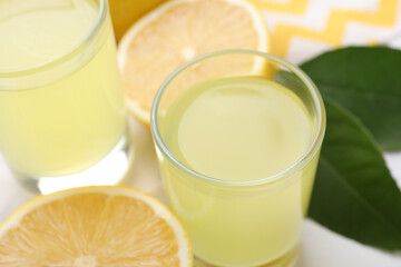 Tasty limoncello liqueur and lemons on table, closeup