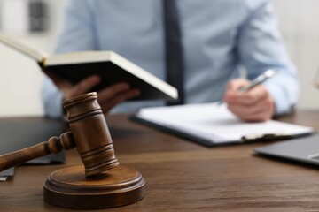 Lawyer working at wooden table indoors, focus on gavel