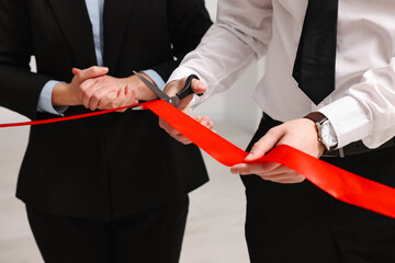 People cutting red ribbon with scissors on blurred background, closeup