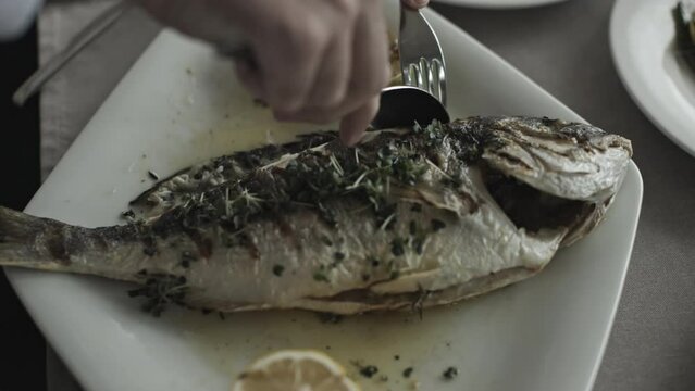 Skillful Chef Demonstrates Proper Fish Cutting Technique on a Plate
